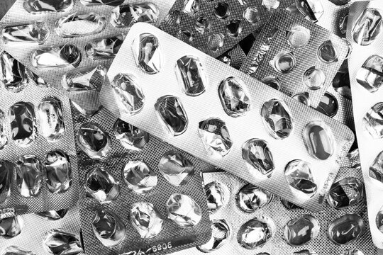 empty pill blisters and one pill top view black and white photo,