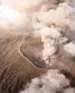 Aerial view of the majestic smoking volcano with a dramatic crater and ash, Sukapura, East Java, Indonesia.