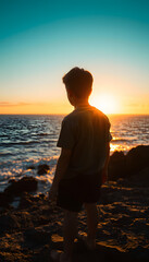 Fototapeta premium Lonely boy watching sunset across the ocean isolated with white highlights, png