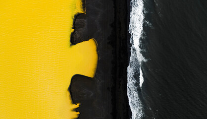 Aerial view of striking yellow surface and black sand along the vibrant ocean waves, Highlands, Iceland.