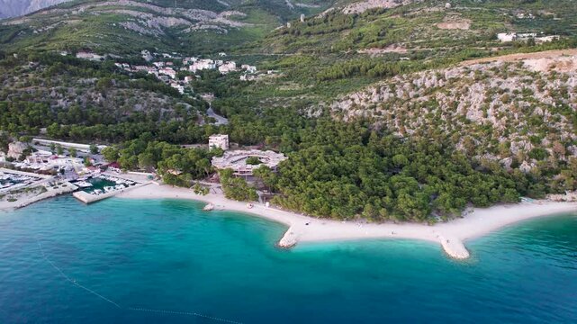 Aerial view of the picturesque Ramova harbour with turquoise sea and serene beach surrounded by lush forests and mountains, Baska Voda, Croatia.