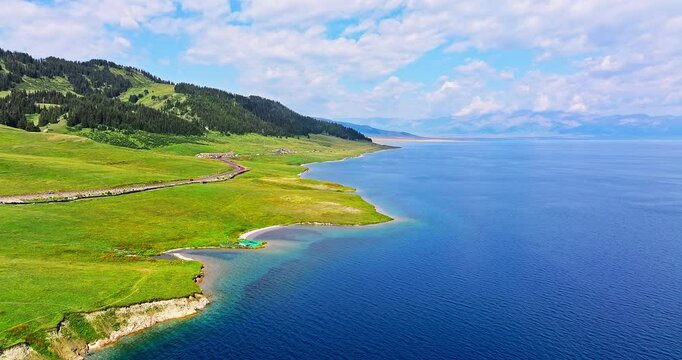 Aerial video of the beautiful Sayram Lake natural landscape in Xinjiang. blue lake and green grassland pasture scenery in China.