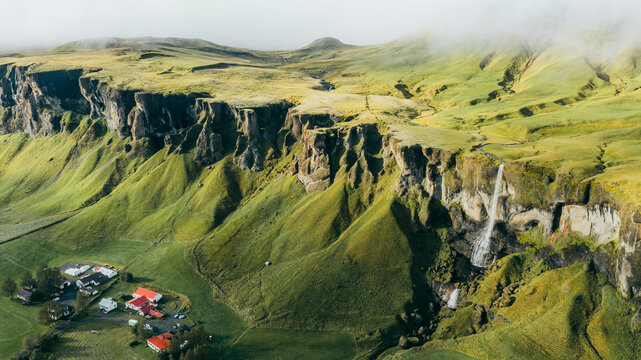 Aerial view of the majestic Foss a Sidu waterfall surrounded by lush greenery and dramatic cliffs in Skaftarhreppur, Iceland.