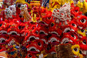 Fototapeta premium A close up shot of multiple red dragon masks with fur and decorative details. Colorful plastic toys and paper lanterns in the background