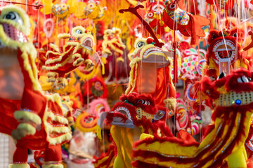 Obraz premium A close up shot of multiple red dragon masks with fur and decorative details. Colorful plastic toys and paper lanterns in the background