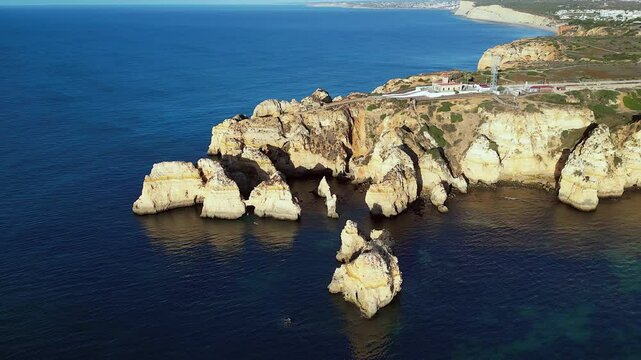 Golden evening aerial orbits headland lighthouse, Ponta da Piedade PRT