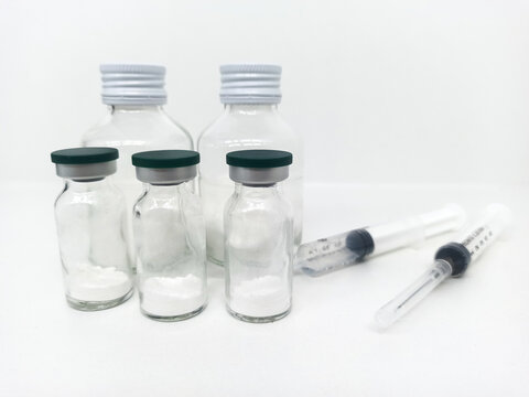 Medical vials and syringes are arranged on a white background to represent clinical preparation.