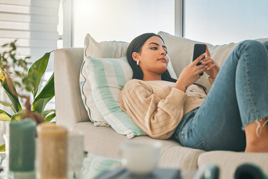 Woman, relax and phone on sofa at house with communication, social media and reading online ebook. Girl, rest and mobile with texting contact, review email and morning news of networking notification