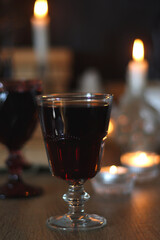 Books, lit candles, red wine, snacks and various deocration on the table. Dark academia or Halloween concept. Selective focus.