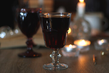 Books, lit candles, red wine, snacks and various deocration on the table. Dark academia or Halloween concept. Selective focus.