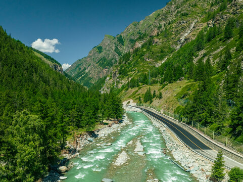 Aerial view of beautiful alps with a river and road surrounded by lush forest, Cogne, Italy.