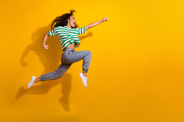 Full body portrait of nice young girl jump run empty space wear striped t-shirt isolated on yellow color background