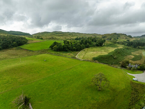 Aerial view of lush green fields and rolling hills under a cloudy sky, Lochgilphead, Scottish Highlands, United Kingdom.