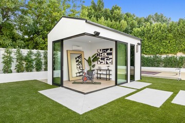 Modern backyard gym with glass walls and greenery.