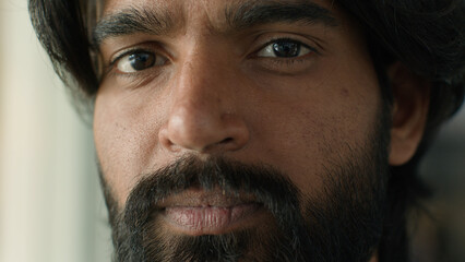 Obraz premium Close-up ethnicity male face serious pensive bearded indian man guy ethnic businessman customer looking at camera gaze with brown eyes client ophthalmology clinic good healthy vision medical procedure