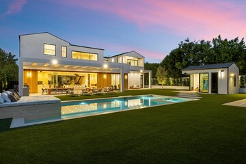 Luxury modern home with pool at dusk.