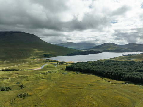 Aerial view of serene Loch Tulla surrounded by majestic mountains and lush greenery, Bridge of Orchy, United Kingdom.
