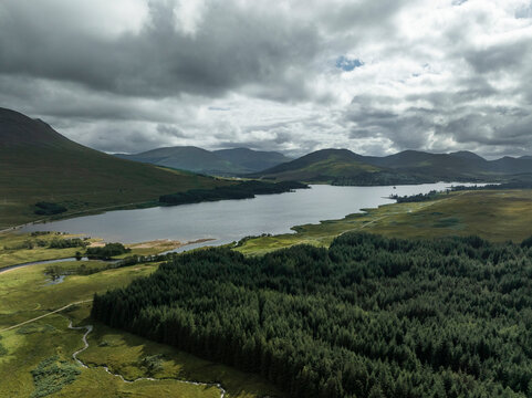 Aerial view of serene Loch Tulla surrounded by majestic mountains and lush forest, Bridge of Orchy, Scotland.