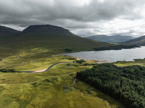 Aerial view of Loch Tulla surrounded by majestic mountains and lush forests, Bridge of Orchy, United Kingdom.