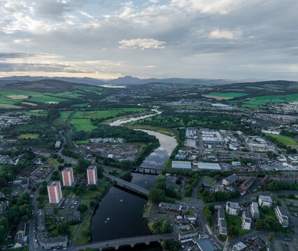 Aerial view of the scenic River Clyde surrounded by historic buildings and lush greenery at sunset, Dumbarton, United Kingdom.