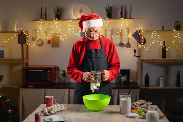 Retiree sifting flour while preparing Christmas gingerbread dough