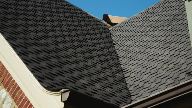 Close-up pan shot of a gutter attached to a newly installed roof, showcasing clean lines and quality craftsmanship. Ideal for roofing and home exterior projects.