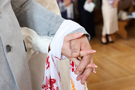 Church wedding ceremony. The hands of the newlyweds are tied with an embroidered cloth.