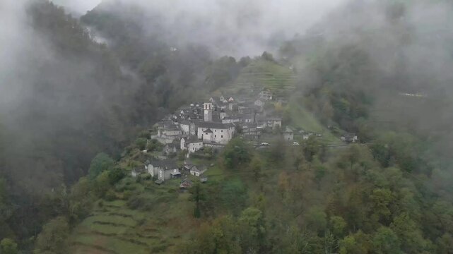 Drone footage flying through the fog unvealing of the town the Corippo, Valle Verzasca