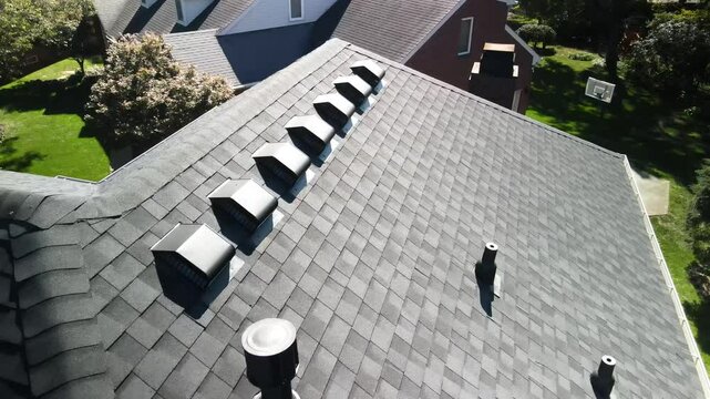 Aerial drone shot focusing on the vents of a newly installed roof. Perfect footage for showcasing roofing ventilation systems and construction details.