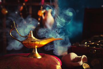 Precious golden magic lamp with smoke and wooden chest with coins.