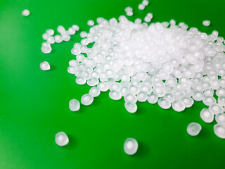 Virgin polypropylene plastic granules on a green background, this polymer is one of the main ingredients in the food grade plastic industry.