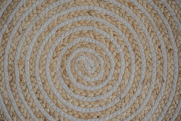 Intricate spiral design of woven natural fibers on a textured circular mat