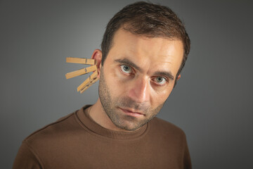 Clothespins on a caucasian male ear.