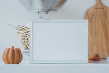White frame on a kitchen countertop with decorative pumpkin and wooden board for fall decor ideas