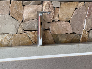 Modern Chrome Faucet Against Rustic Stone Wall