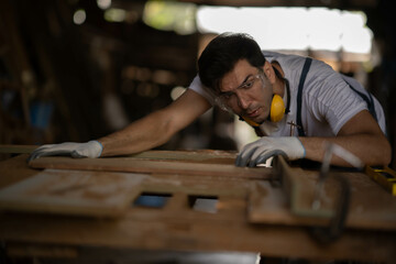 Portrait of Young White carpenter man checking  peice of furniture looking at it and measure it...