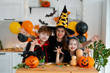 Happy family preparing for Halloween. Mother and children in carnival costumes at home in the...