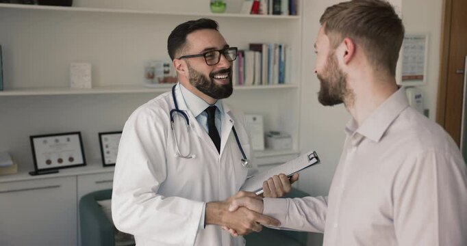 Man physician consulting to male patient, share optimistic news about cured disease, good health condition, shake hands. Positive communication, effective treatment, professional medical care provider