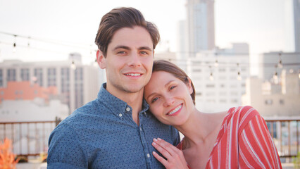 Fototapeta premium Portrait Of Romantic Couple Hugging On Rooftop Terrace With City Skyline In Background