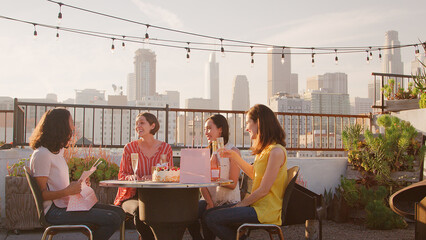 Group Of Female Friends Celebrating Birthday On Rooftop Terrace With City Skyline In Background