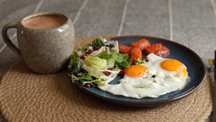Two sunny eggs with orange yolks rest next to salmon slices, fresh salad with pomegranate seeds, and creamy smoothie in gray mug, highlighting eco-conscious healthy lifestyle meal.
