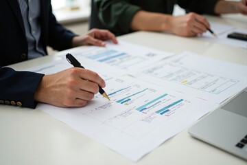 Hands of two individuals engaged in reviewing project documents at workplace, focusing on details and notes for strategic planning and analysis