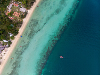 Aerial view of a tropical beach with clear waters and lush greenery.