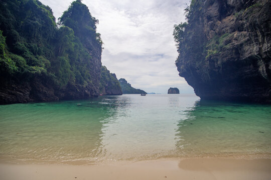 Serene beach with towering cliffs and a distant island.