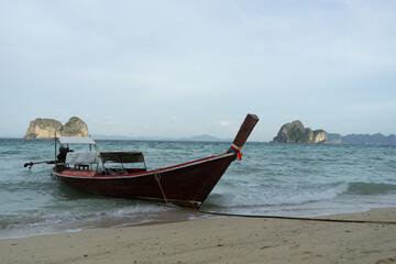 A traditional boat rests on the shore against a backdrop of distant islands.