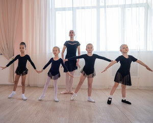 Children's ballet school. Caucasian woman teaching ballet to little girls. 