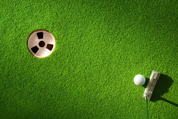Top view of golf ball and putter ready putting to golf hole.