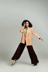 A stylish woman confidently poses in a chic oversized blazer with wide legged pants and heels.