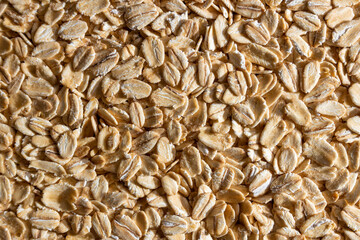 Uncooked Oat Flakes background - Top View, Flat Lay. Scattered Dry and Raw Oat Flakes. Healthy Breakfast and Diet Eating Ingredients