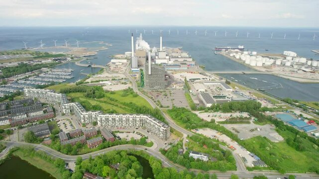 Aerial view of the modern copenhill power plant with wind turbines and a bustling harbour along the canal, copenhagen, denmark.